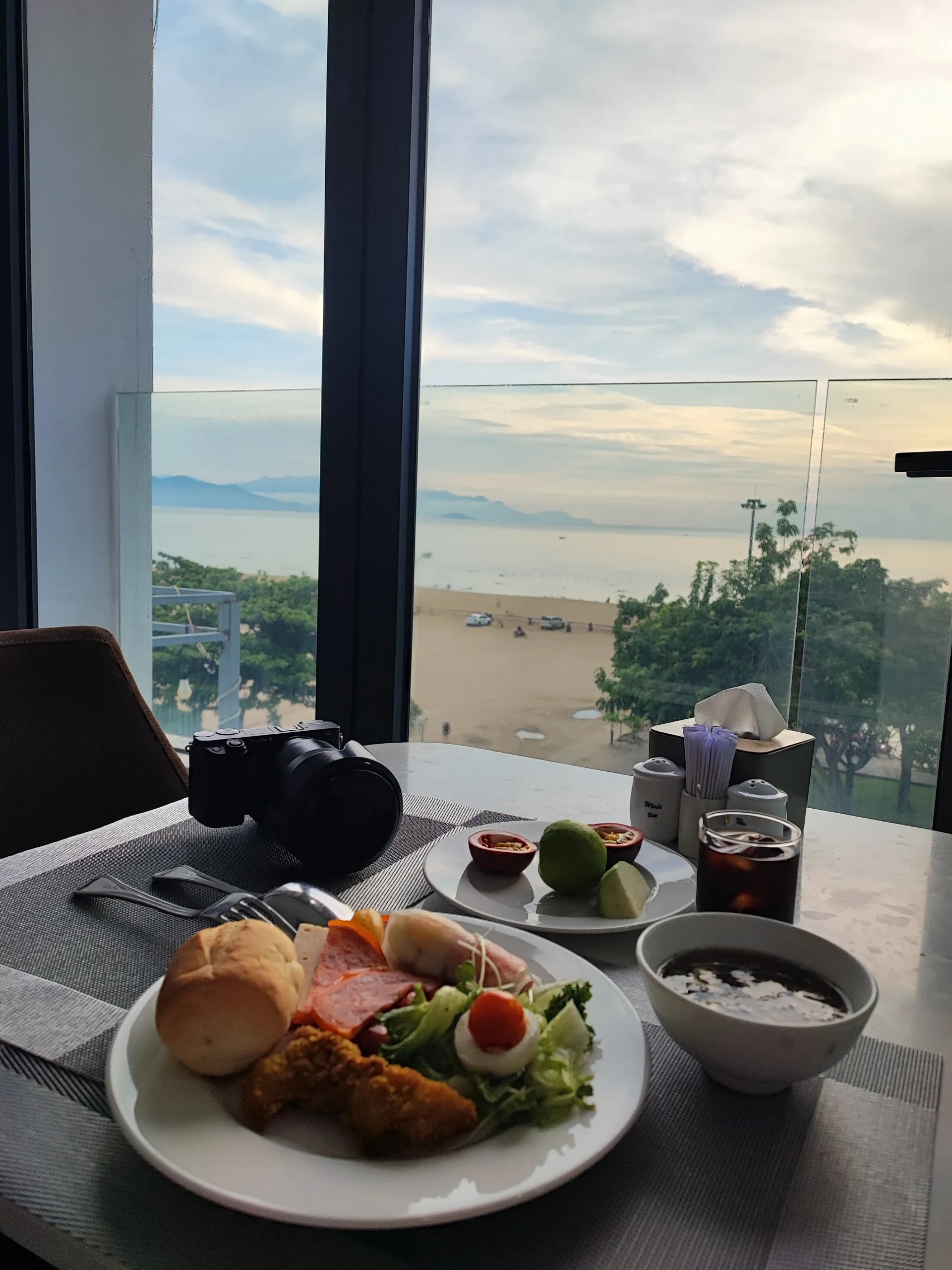 Đĩa buffet sáng đặt cạnh cửa kính nhìn ra bãi biển tại nhà hàng La Vague