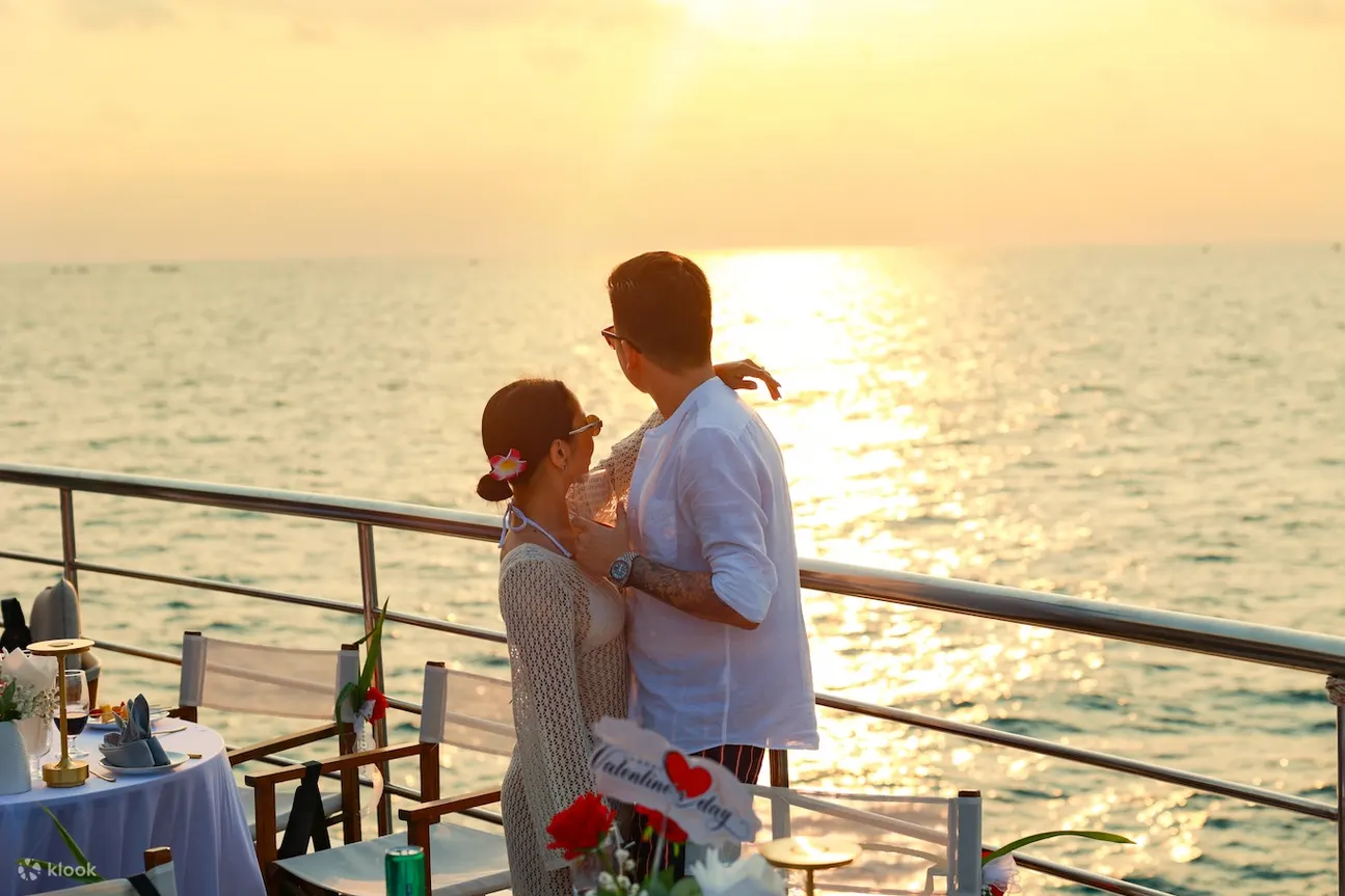 Cặp đôi ngắm hoàng hôn lãng mạn bên bàn tiệc riêng trên du thuyền Cặp đôi ngắm hoàng hôn lãng mạn bên bàn tiệc riêng trên du thuyền
